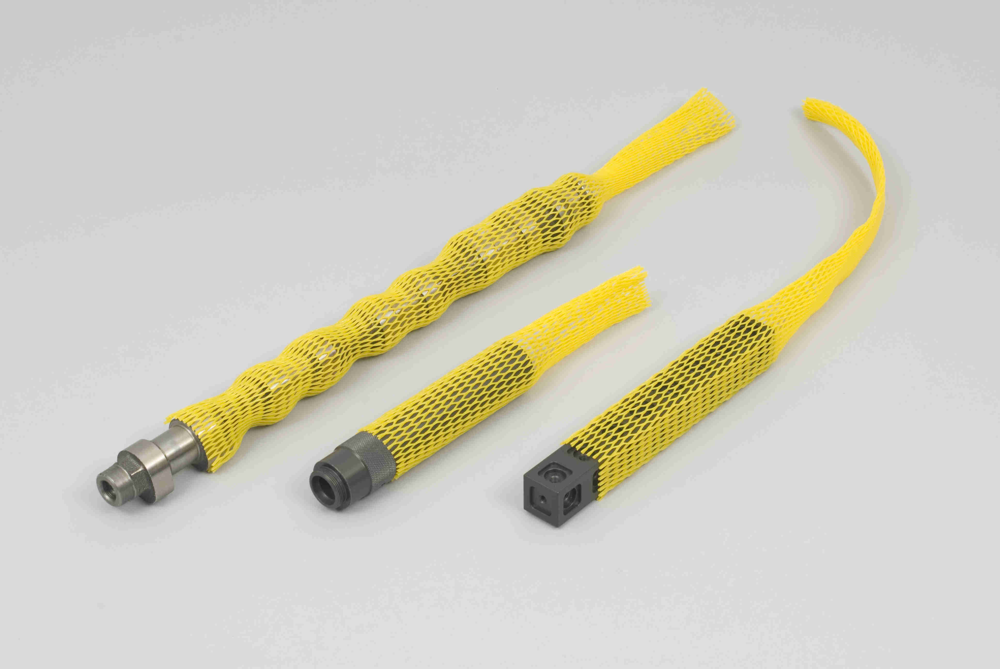 Kunststoff-Netzschutzschläuche in gelb mit Werkstücken, liegend